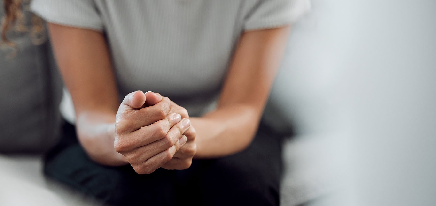 Woman clutching her hands as she speaks to her therapist